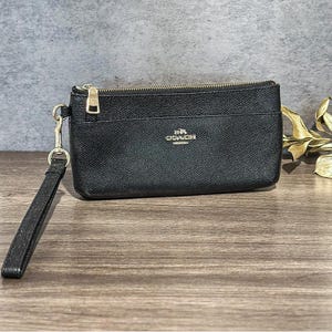 Pochette Coach en cuir noir avec bracelet et fermeture à glissière avec finitions dorées Petite pochette Coach fabriquée en Thaïlande Sac de soirée minimaliste