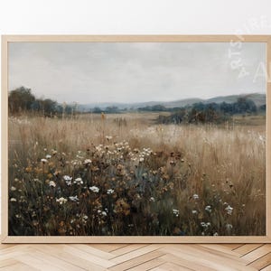 May include: A framed landscape print depicting a field of tall, dry grass and wildflowers beneath a cloudy sky. The artwork uses a muted palette of browns, greens, and whites, with a wooden frame.