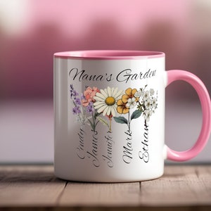 Può includere: Tazza in ceramica bianca con bordo e manico rosa. La tazza presenta un motivo floreale con il testo "Nana's Garden" e i nomi "Cindy, James, Jennifer, Mark, Ethan".