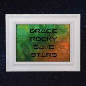 Op de afbeelding: Witgelijste kunstdruk met de woorden "GRACE ROCKY SAVE STARS" in zwarte tekst op een groene, oranje en gele achtergrond. De achtergrond heeft een pixelachtig effect. Het kunstwerk is geplaatst tegen een sterrenhemel.