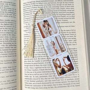 Puede incluir: Un marcapáginas con tres fotos rectangulares de una familia, con las palabras "Family" y "Thank you". El marcapáginas tiene una borla beige y está en un libro abierto.