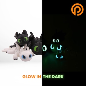 The same dragon photographed in a darkened room, its eyes and accent markings glowing pale green-blue. The body outline is faintly visible, showing where the glow pigment sits.