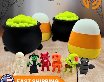 May include: Halloween-themed decorations featuring a black cauldron with green foam, candy corn, and miniature figurines of a skeleton, witch, devil, pumpkin, zombie, and bat. The image includes the text "FAST SHIPPING".
