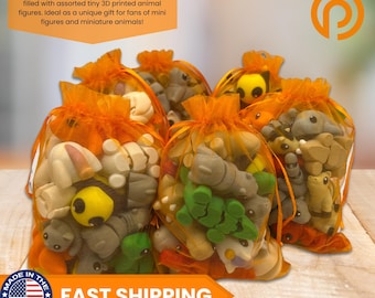 Op de afbeelding: Oranje organza cadeauzakjes gevuld met diverse kleine 3D-geprinte dierenfiguren. De tekst "GIFT BAG READY" en "FAST SHIPPING" is zichtbaar op de afbeelding.