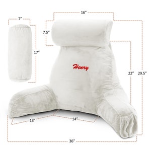 May include: White plush reading pillow with armrests and a headrest. The pillow is 91 cm wide, 75 cm tall, and 56 cm deep. The headrest is 41 cm wide and 19 cm tall. The pillow has the name "Henry" embroidered on it.