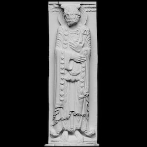 Puede incluir: Una detallada escultura en relieve de color blanquecino de una figura vestida con una túnica y con un halo. La figura tiene barba y sostiene un objeto, posiblemente un libro o un pergamino. La escultura está sobre un fondo rectangular.