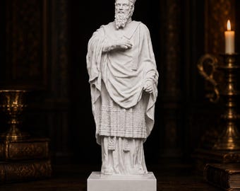 Könnte beinhalten: Eine weiße Statue einer bärtigen Figur, die eine hohe Mitra und geschichtete liturgische Gewänder mit komplizierten geometrischen Mustern am Saum trägt. Die Figur steht auf einem rechteckigen Sockel und hält eine Hand ehrfürchtig auf der Brust.