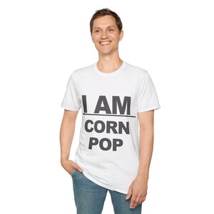 Può includere: Una maglietta bianca con testo nero che dice "I AM CORN POP".