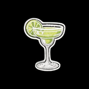 May include: An embroidered patch in the shape of a margarita glass with a lime wedge garnish. The design features shades of light green and yellow thread for the drink, with a white border and white thread detailing the glass stem and base.