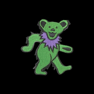 May include: An embroidered patch featuring a stylized green bear with a purple ruff around its neck. The bear is depicted in a walking pose with black outlines, black ears, and a black nose and mouth, all set against a solid black background.