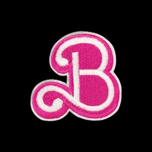 May include: A decorative embroidered patch in the shape of the capital letter B. The letter features a vibrant hot pink thread color with a thick, contrasting white border outline, showcasing a detailed stitched texture throughout the design.