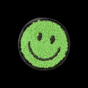 Op de afbeelding: Een ronde geborduurde patch met een fel limoengroen smileygezicht. De patch heeft een getextureerd oppervlak van lussen garen met zwarte stiksels die twee ovale ogen en een brede, gebogen mond vormen, omlijnd door een stevige zwarte rand.