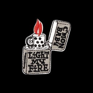 May include: An embroidered patch shaped like an open metal lighter with a red flame. The lighter body features the black text LIGHT MY FIRE, while the open lid displays the black text CMON BABY. The design uses grey, black, and red thread.