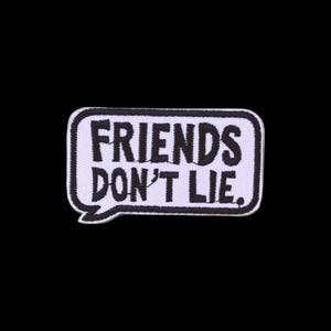 May include: A rectangular embroidered patch shaped like a speech bubble with a white background and a thick black border. The text FRIENDS DON'T LIE is stitched in bold black capital letters across the centre of the patch surface.