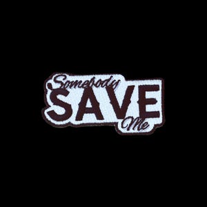 Pode incluir: Um emblema bordado com o texto Somebody SAVE Me. A palavra SAVE é exibida em letras maiúsculas grandes, em negrito e na cor castanho-escuro, enquanto as palavras Somebody e Me estão escritas numa fonte cursiva menor e de cor castanho-escuro.