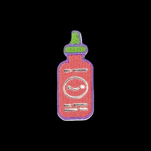 May include: A hot sauce bottle embroidered patch featuring a red body, a bright green cap, and a purple border. The design includes a central white circular emblem with a small white graphic inside and horizontal white lines representing text.