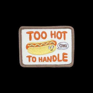 May include: A rectangular embroidered patch with a white background and a brown border. It features a yellow hot dog character with a face, the orange text TOO HOT TO HANDLE, and a small white speech bubble containing the word OW! in brown.