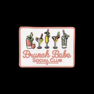 May include: A rectangular embroidered patch with a white background and a coral border. It features five colorful cocktail illustrations above the coral-colored text that reads Brunch Babe SOCIAL CLUB in a script and block font combination.