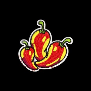 Puede incluir: Un parche bordado que presenta tres chiles dispuestos en un grupo. Cada chile está representado en rojo vibrante con reflejos amarillos brillantes y un tallo verde, todo delineado con un borde blanco grueso sobre un fondo negro.
