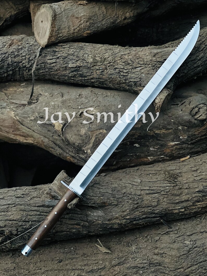 May include: A large, silver sword with a serrated edge and a wooden handle. The handle is dark brown with silver accents. The text "Jay Smithy" is visible on the surface.