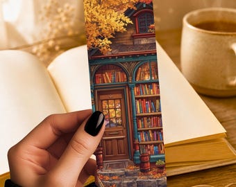 May include: A rectangular bookmark featuring a detailed illustration of a bookstore entrance with a wooden door, tall shelves filled with colorful books, and a tree with golden autumn leaves. The text LUNA AND LOOM is printed at the bottom.