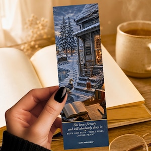 May include: A bookmark featuring a winter scene with a snow-covered house, trees, and a duck. The bookmark has text that reads "She loves fiercely and will absolutely deny it." and the author's name. The bookmark is held over an open book.