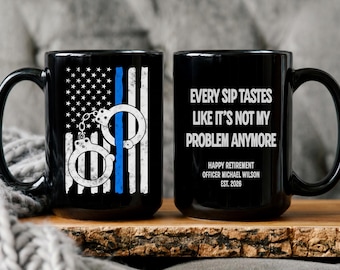 Könnte beinhalten: Schwarze Keramik-Tasse mit einem verwitterten amerikanischen Flaggen-Design, Handschellen und einem blauen Streifen. Die andere Seite hat den Text "EVERY SIP TASTES LIKE IT'S NOT MY PROBLEM ANYMORE" und Ruhestandsdetails.