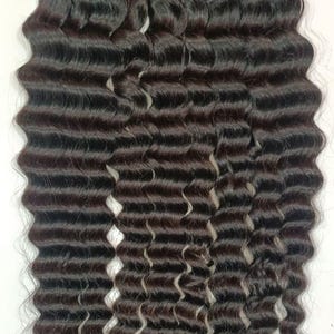 May include: Dark brown bundles of wavy hair extensions. The hair has a deep wave pattern, with each strand appearing thick and full. The extensions are arranged in neat bundles, ready for use. The overall look is of a natural, voluminous hairstyle.