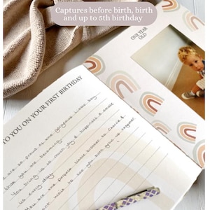 May include: A white journal with a rainbow design and the text "To You On Your First Birthday" and "One Year Old". The journal has a photo slot with a picture of a young boy.