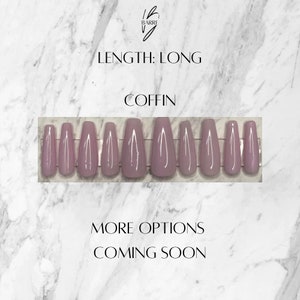 May include: A set of long, coffin-shaped false nails in a muted mauve color. The nails are arranged in a row, showcasing their shape and length. The image includes text that reads "Length: Long", "Coffin", "More Options Coming Soon".