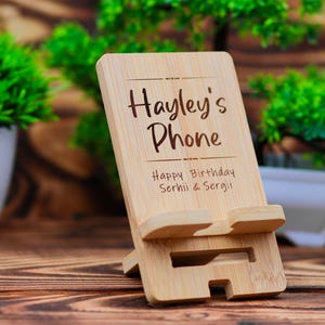 May include: A wooden phone stand with the text "Hayley's Phone" and "Happy Birthday Serhii & Sergii" engraved on it.