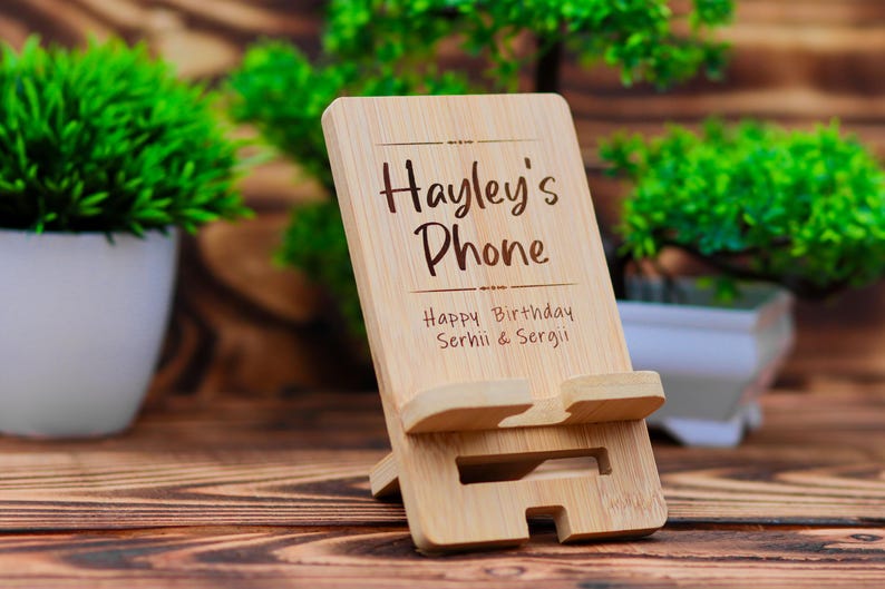 May include: A wooden phone stand with the text "Hayley's Phone" and "Happy Birthday Serhii & Sergii" engraved on it.