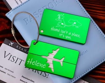 May include: Two green luggage tags with a silver chain. One tag has a map of the UK with the text "Home isn't a place, it's you." The other tag has a cutout of an airplane and the text "Helene Paris!"