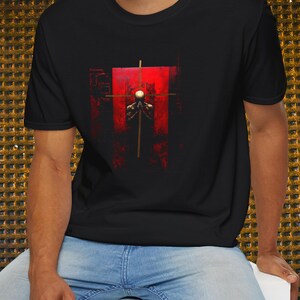Könnte beinhalten: Ein schwarzes T-Shirt mit einem grafischen Druck einer Person, die vor einem roten Kreuz steht. Die Person trägt ein weißes Hemd und hat die Hände zum Gebet gefaltet.