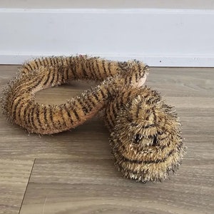 May include: A plush toy snake with brown and black stripes. The snake is curled up in a coil shape with its head facing the camera.