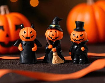 Könnte beinhalten: Drei Halloween-Kürbisfiguren, die als Teufel, Hexe und Gentleman verkleidet sind. Die orangefarbenen Kürbisköpfe haben geschnitzte Gesichter und tragen schwarze Outfits. Eine dekorative orangefarbene Schleife befindet sich im Vordergrund, mit orangefarbenen Kürbissen im Hintergrund.