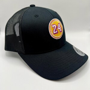 May include: Black trucker hat with a yellow and purple circle patch that says "24" on it.