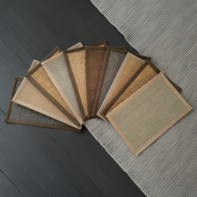 K&ouml;nnte beinhalten: Eine Auswahl rechteckiger Teppiche in neutralen Farbt&ouml;nen wie Beige, Braun und Grau. Jeder Teppich hat eine strukturierte Oberfl&auml;che und einen kontrastierenden Rand. Die Teppiche sind auf einem dunkelgrauen Holzboden und einem hellgrauen Teppich angeordnet.