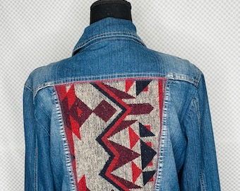 May include: Blue denim jacket with a colorful geometric design on the back. The design features red, black, and gray patterns. The text "Gitty Up Cycle" is above the jacket.
