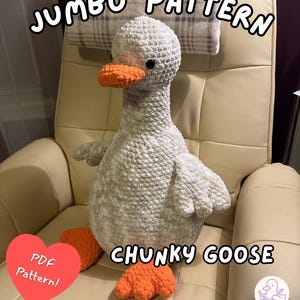 Puede incluir: Un ganso grande de crochet blanco y beige con pico y patas naranjas. El ganso está sentado en una silla color crema. El texto de la imagen dice "JUMBO PATTERN" y "CHUNKY GOOSE". Un corazón dice "PDF Pattern!"
