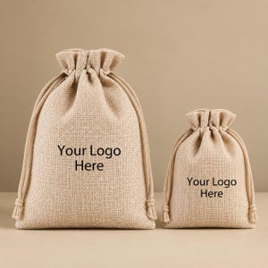 May include: Two beige burlap drawstring pouches of different sizes, each featuring the black text "Your Logo Here" printed on the front. The bags have a textured woven fabric construction with matching beige cord ties at the top closure.