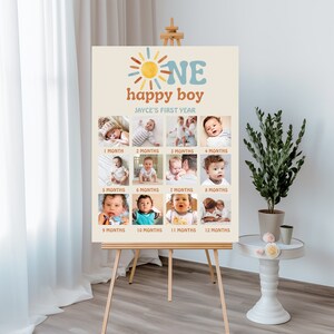 K&ouml;nnte beinhalten: Ein beiger Poster mit einer Sonnengrafik und dem Text "ONE happy boy" in Blau und Orange. Das Poster zeigt eine Collage aus 12 Fotos eines kleinen Jungen in verschiedenen Altersstufen, von 1 Monat bis 12 Monate.