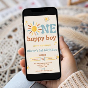 May include: A smartphone displays a birthday invitation with a retro design. The invitation reads "ONE happy boy" with a sun graphic. Details include the date, time, and location for Oliver's 1st birthday celebration.