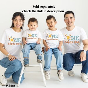 Puede incluir: Camisetas blancas a juego para la familia con un gr&aacute;fico de sol y la palabra "ONE". Las camisetas tienen las frases "happy mom", "happy boy", "happy brother" y "happy dad". Tambi&eacute;n se ve el texto "Sold separately check the link in description".