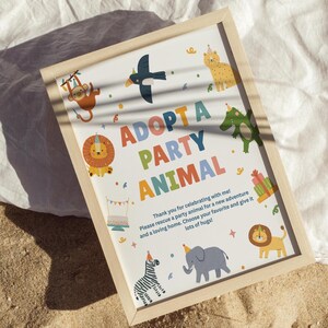 May include: A framed print with the words "ADOPT A PARTY ANIMAL" in colorful letters. The print features cartoon animals like a monkey, lion, zebra, and elephant, with party hats and confetti. The text below reads "Thank you for celebrating with me!"