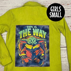 Op de afbeelding: Een limoengroen corduroy jack met een patch op de rug. De patch toont een cartoonfiguur met de tekst "This is the way".