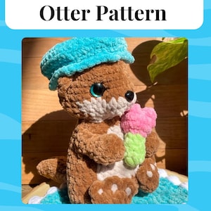Puede incluir: Una nutria de crochet marrón que lleva un gorro de crochet azul y sostiene una paleta de hielo de crochet rosa y verde. La nutria está sentada sobre una superficie de crochet azul y blanco. Copyright © Summerstitches.crochet2024 todos los derechos reservados.