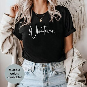 May include: A black t-shirt with the text "Whatever." written in white cursive script.