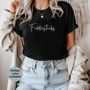 Puede incluir: Una camiseta negra con el texto "Fiddlesticks" en letra blanca cursiva.
