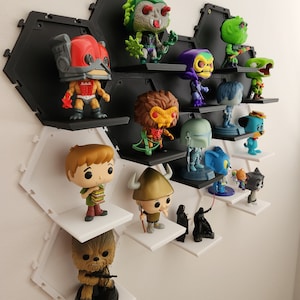 May include: A hexagonal shelf unit with white and black shelves displays a collection of pop culture figurines. The figurines include characters from Star Wars, Scooby Doo, and other popular franchises.